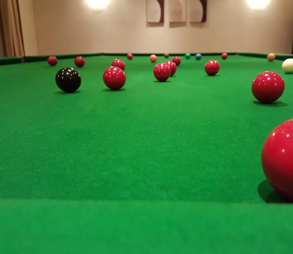 Bolas de snooker vermelhas alinhadas sobre o pano verde de uma mesa